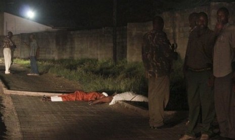 Security forces stand next to the bodies of slain muslim cleric Abubakar Shariff Ahmed, center, and another man whose identity has not yet been established, center-left, on a highway in Mombasa, Kenya Tuesday, April 1, 2014. 