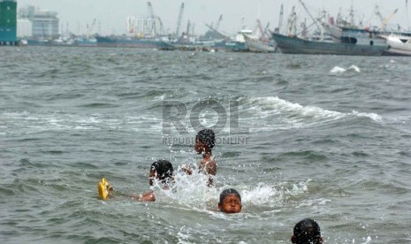  Sejumlah anak berenang di pinggiran Pantai Muara Baru yang penuh dengan limbah kapal laut, Jakarta Utara, Senin (8/9). (Republika/Raisan Al Farisi)