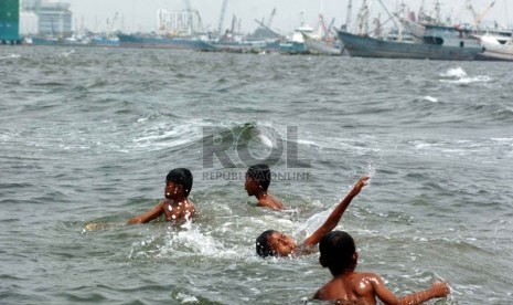  Sejumlah anak berenang di pinggiran Pantai Muara Baru yang penuh dengan limbah kapal laut, Jakarta Utara, Senin (8/9). (Republika/Raisan Al Farisi)