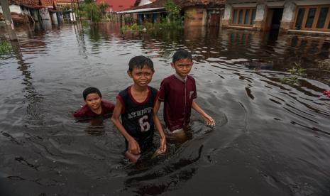 Sejumlah anak berjalan melewati banjir rob di Tirto Gang 12, Pekalongan, Jawa Tengah, Rabu (25/5/2022). Menurut Wali Kota Pekalongan Afzan Arslan Djunaid, akibat tingginya air laut pasang menyebabkan sejumlah wilayah di Kota Pekalongan dengan 19 ribu jiwa dan sekitar 5.000 KK terdampak banjir rob dengan ketinggian antara 5-60 centimeter. 