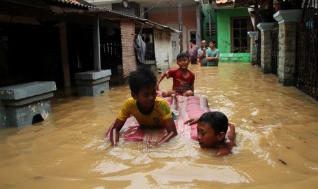 Sejumlah anak bermain air banjir yang merendam kawasan permukiman penduduk Cililitan Kecil, Jakarta, Jumat (26/4/2019).