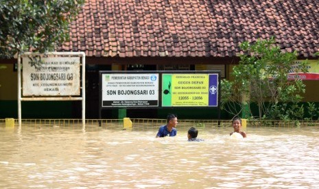 Sejumlah anak bermain air di area gedung sekolah yang terendam banjir di kawasan pemukiman penduduk bantaran Sungai Citarum, Kedungwaringin, Kabupaten Bekasi, Jawa Barat, Senin (14/11). 