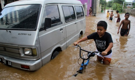 Sejumlah anak bermain genangan air banjir di kelurahan Bukit Duri, Jakarta, Selasa (8/3). 