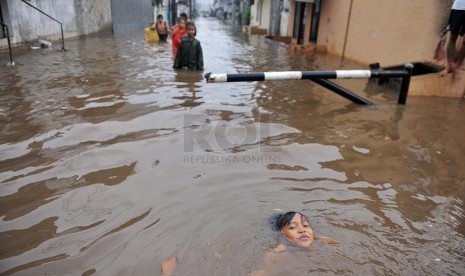 Sejumlah anak bermain saat banjir merendam perumahan Jatikramat Indah di Bekasi, Jawa Barat, Jumat (28/3).