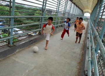 Sejumlah anak bermain sepak bola dengan memanfaatkan jembatan penyebrangan di kawasan Kemayoran, Jakarta, Sabtu (17/3). (Republika/Agung Fatma Putra)