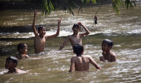 Sejumlah anak memanfaatkan hari libur dengan bermain di aliran Sungai Ciliwung, Depok, Jawa Barat, Jumat (19/4/2019).