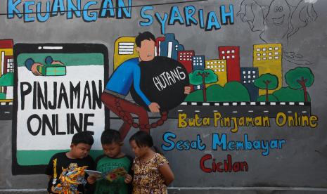 Sejumlah anak membaca bersama di dekat dinding bermural di kawasan Tempurejo, Surabaya, Jawa Timur, Selasa (7/9/2021). Mural tersebut sebagai sarana imbauan kepada masyarakat terhadap bahaya pinjaman daring atau online (pinjol) ilegal yang sekarang lagi marak.  