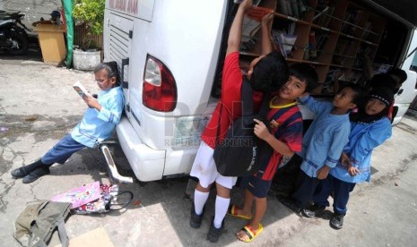  Sejumlah anak membaca buku di mobil perpustakaan keliling di Penjaringan, Jakarta Utara, Jumat (21/3). (Republika/Wihdan)