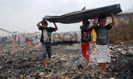  Sejumlah anak mengangkut barang yang tersisa dari kebakaran yang melanda pemukiman semi permanen di Jalan Kapuk Raya, Kapuk, Jakarta Utara, Selasa (11/12).  (Republika/Agung Fatma Putra)