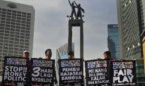 Sejumlah anggota dari Republik Aeng-aeng dan Pasoepati memegang poster bertemakan pemilu damai saat aksi kampanye damai di Bundaran HI, Jakarta, Ahad (6/4).