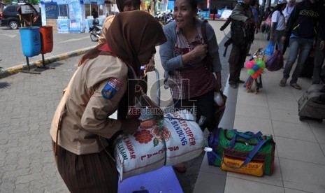 Sejumlah anggota gerakan pramuka penegak pandega Kota Cilegon membantu calon penumpang yang hendak menuju pelabuhan Merak, Banten, Ahad (4/8). (Republika/Rakhmawaty La'lang)