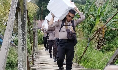 Sejumlah anggota kepolisian memanggul logistik Pemilu serentak 2019 melintasi hutan menuju Dusun Buntan di Desa Bungkang, Kecamatan Sekayam, Kabupaten Sanggau, Kalimantan Barat, Selasa (16/4/2019).