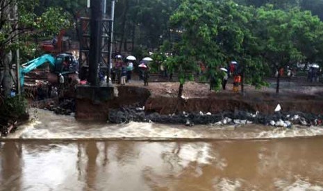   Sejumlah anggota Kopassus menambal tanggul jebol di aliran Banjir Kanal Barat, Menteng, Jakarta Pusat, Jumat (18/1).