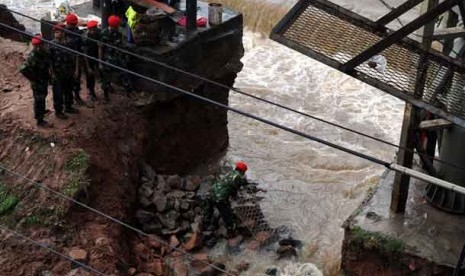 Sejumlah anggota Kopassus menambal tanggul jebol di aliran Banjir Kanal Barat, Menteng, Jakarta Pusat, Jumat (18/1).