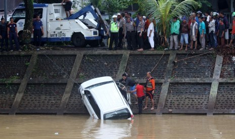 Sejumlah anggota Polisi, Badan Penanggulangan Bencana Daerah (BPBD) Kota Padang dan warga mengevakuasi mobil yang masuk dalam banjir kanal Bandar Bakali, Padang, Sumatera Barat, Senin (21/1/2019)