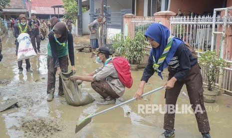 Sejumlah anggota Pramuka membersihkan lumpur sisa banjir di perumahan Jatiasih, Bekasi, Jawa Barat, Sabtu (18/1/2020). 