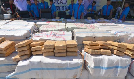 Sejumlah anggota Satnarkoba Polres Lampung Selatan berada disamping tumpukan ribuan paket daun ganja kering hasil tangkapan saat gelar perkara kasus kejahatan narkotika di Mapolres Lampung Selatan, Kamis (9/7). 