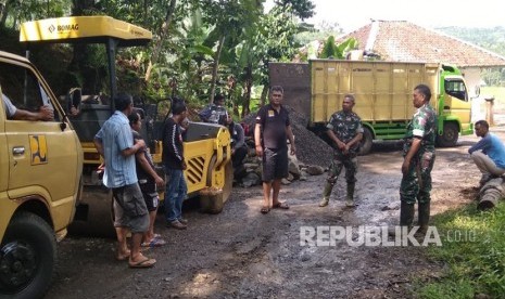 Sejumlah anggota TNI dan masyarakat tengah melakukan pengadaan material pengaspalan jalan yang merupakan bagian dari program Tentara Manunggal Membangun Desa (TMMD). 