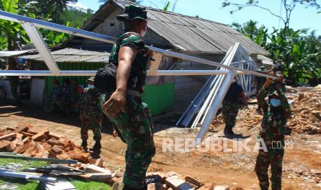 Sejumlah anggota TNI mengangkat rangka atap baja ringan yang akan digunakan untuk membangun rumah semi permanen di Jogomulyan, Malang, Jawa Timur, Jumat (16/4/2021). Pemerintah setempat akan mendirikan rumah semi permanen bagi korban gempa Malang dengan target pembangunan sepuluh hari agar bisa segera digunakan.