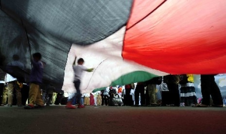 Sejumlah bocah bermain dibawah bendera Palestina saat aksi simpatik untuk Gaza di Bunderan HI,