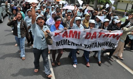  Sejumlah buruh membentangkan spanduk ketika berunjuk rasa menuntut revisi dan penyesuaian upah minimum kabupaten/kota (UMK).