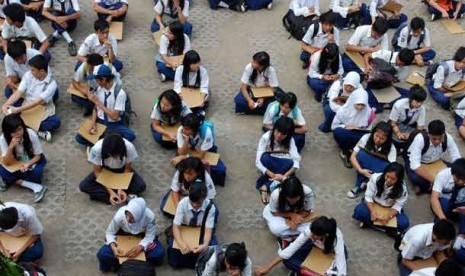 Sejumlah calon siswa duduk di lapangan ketika mengantri untuk daftar di sekolah.  (ilustrasi)