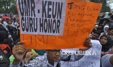  Sejumlah guru honorer Jawa Barat membawa poster melakukan unjuk rasa menuntut kesejahteraan di depan Gedung Sate,Kota Bandung, Senin (31/10). (Republika/Mahmud Muhyidin)