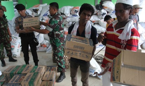 Sejumlah imigran etnis Rohingya, Myanmar dan Bangladesh dibantu personel TNI dan Polri mengangkat barang bantuan warga, ketika dilakukan proses pemindahan dari penampungan sementara, Pangkalan Susu, Langkat, Sumatera Utara, Senin (18/5).