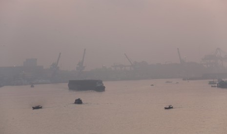 Sejumlah kapal nelayan dan pengangkut batubara melintas di sungai musi yang diselimuti kabut asap, Palembang, Senin (27/7).