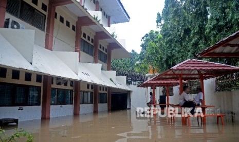  Sejumlah karyawan berjaga saat banjir menggenagi sekolah SMA Negeri 8 , Bukit Duri, Jakarta, Kamis (16/2).