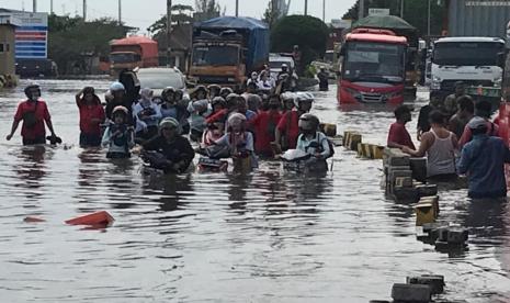 Sejumlah karyawan di kawasan Berikat Tanjung Emas Semarang menuntun sepedamotor melalui jalan yang tergenang air rob, di jalan Coaster kompleks Tanjung Emas Kecamatan Semarang Utara, Kota Semarang, Senin (23/5). Sejumlah industri di kawasan berikat ini terpaksa menghentikan produksi karena genangan rob cukup tinggi.