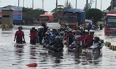 Sejumlah karyawan di kawasan Berikat Tanjung Emas Semarang menuntun sepedamotor melalui jalan yang tergenang air rob, di jalan Coaster kompleks Tanjung Emas Kecamatan Semarang Utara, Kota Semarang, Senin (23/5). Sejumlah industri di kawasan berikat ini terpaksa menghentikan produksi karena genangan rob cukup tinggi.