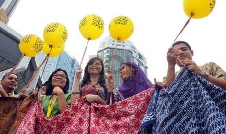 Sejumlah karyawan membentangkan kain batik di sebuah gedung di Jalan Merdeka Barat, Jakarta, Selasa (2/10). (Aditya Pradana Putra/Republika)