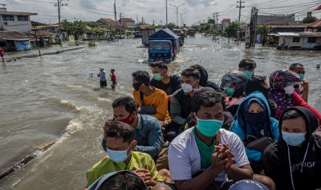 Sejumlah karyawan RS Sultan Agung menumpang truk evakuasi BPBD Semarang untuk dapat menembus banjir yang merendam jalur Pantura Jalan Raya Kaligawe - Genuk, Semarang, Jawa Tengah, Jumat (26/2/2021). BPBD Kota Semarang bersama BPBD Jawa Tengah menyiagakan lima armada evakuasi yang diprioritaskan mengangkut pasien, karyawan maupun tenaga medis rumah sakit untuk menembus jalur tersebut yang hingga Jumat (26/2) masih terendam banjir dengan ketinggian mencapai 1 meter.