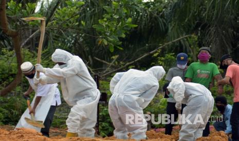 Sejumlah keluarga pasien (kanan) memperhatikan tenaga medis dan penggali kubur yang mengenakan alat pelindung diri saat proses pemakaman keluarganya di Tempat Pemakaman Umum (TPU) Tengku Mahmud Palas di Kota Pekanbaru, Riau, Selasa (28/4/2020). Pemerintah Indonesia menyatakan hingga 28 April pukul 12.00 WIB, jumlah kematian akibat COVID-19 mencapai 773 orang dari 9.511 kasus terkonfirmasi positif, sedangkan yang sembuh ada 1.254 orang. 