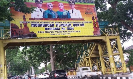 Sejumlah kendaraan melintas di bawah billboard MTQ Nasional XXVI di Kota Mataram, Nusa Tenggara Barat, Kamis (21/7/2016).