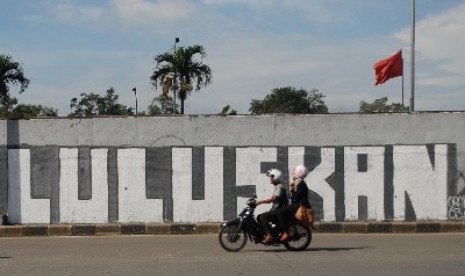 Sejumlah kendaraan melintas di depan mural bertuliskan 