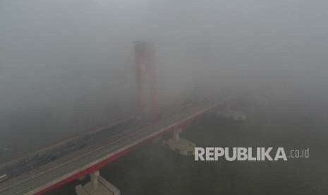 Sejumlah kendaraan melintas diatas jembatan ampera yang tertutup kabut asap di Palembang, Sumatera Selatan, Jumat (5/10). 