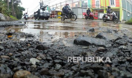 Sejumlah kendaraan melintasi jalan berlubang dan tergenang air di Jalan Raya Tegar Beriman, Cibinong, Kabupaten Bogor, Jawa Barat, Selasa (21/12/2021). Akses jalan kawasan Pemerintah Daerah Kabupaten Bogor tersebut rusak selama berbulan-bulan itu tidak kunjung diperbaiki. 