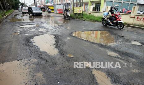 Sejumlah kendaraan melintasi jalan berlubang dan tergenang air di Jalan Raya Tegar Beriman, Cibinong, Kabupaten Bogor, Jawa Barat. 