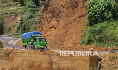 Sejumlah kendaraan melintasi lokasi tanah longsor. 