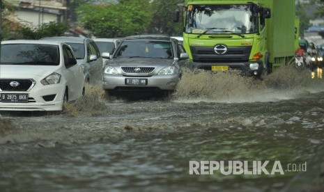 Sejumlah kendaraan melintasi luapan air yang menggenangi jalan di kawasan industri Kahatex, Kecamatan Cimanggung, Kabupaten Sumedang, Selasa (28/3). Banjir di kawasan tersebut itu kerap terjadi meskipun dengan intensitas hujan yang relatif kecil 