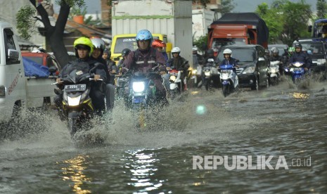 Sejumlah kendaraan melintasi luapan air yang menggenangi jalan di kawasan industri Kahatex, Kecamatan Cimanggung, Kabupaten Sumedang, Selasa (28/3). Banjir di kawasan tersebut itu kerap terjadi meskipun dengan intensitas hujan yang relatif kecil 