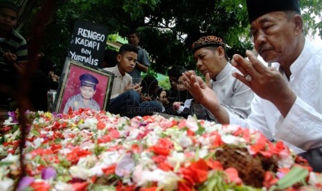   Sejumlah kerabat tengah memanjatkan doa saat pemakaman almarhum Renggo Kadapi di TPU Kampung Asem, Halim, Jakarta Timur, Ahad (4/5).  (Republika/Yasin Habibi)