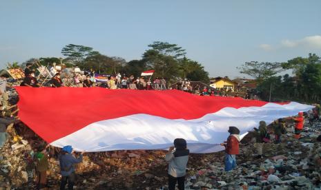 Sejumlah komunitas di Kota Tasikmalaya melakukan aksi pengibaran bendera merah-putih berukuran raksasa di TPA Ciangir, Kota Tasikmalaya, Ahad (15/8). Aksi itu dilakukan untuk menyambut hari kemerdekaan ke-76 Indonesia. 