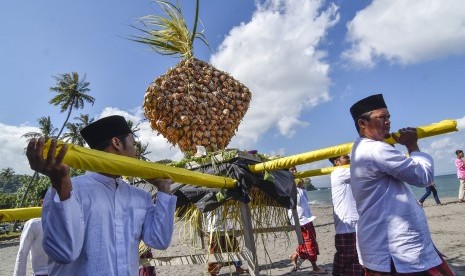 Sejumlah laki-laki mengangkat 'topat' (ketupat) untuk disajikan saat mengikuti tradisi lebaran topat di pantai Batulayar, Lombok Barat, NTB, Rabu (12/6/2019).