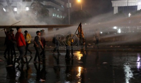    Sejumlah mahasiswa menahan semprotan air dari water cannon saat demo tolak BBM di depan Komplek Parlemen, Jakarta, Senin (17/6) malam.   (Republika/Yasin Habibi)