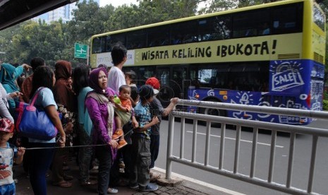 Sejumlah masyarakat mengantre untuk naik Bus Tingkat Pariwisata di Jalan Medan Merdeka Barat, Jakarta Pusat, Jumat (18/4). (Republika/Rakhmawaty La'lang)