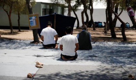 Sejumlah migran tengah melaksanakan shalat di tempat pengungsian