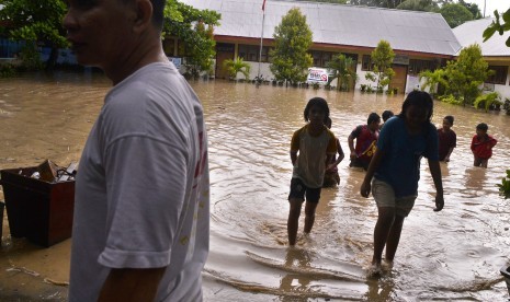 Sejumlah murid sekolah dasar berjalan menembus banjir yang menggenangi sekolah mereka di kawasan permukiman Kecamatan Singkil, Manado, Sulawesi Utara, Jumat (21/10).